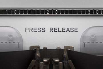 Typing text PRESS RELEASE on vintage manual typewriter. Close up of writes word on white paper....