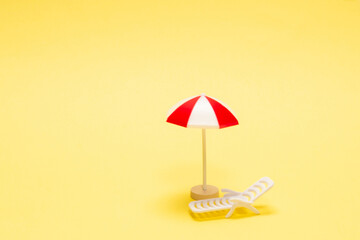 Two sun loungers and a red umbrella on a yellow background.