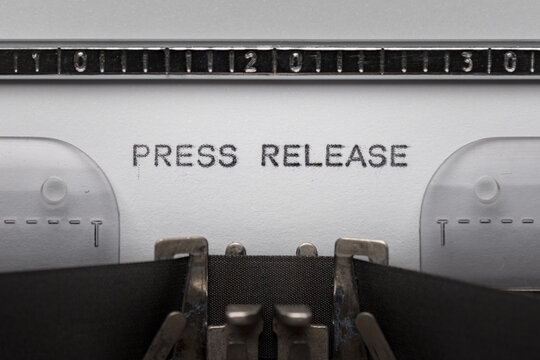 Typing text PRESS RELEASE on vintage manual typewriter. Close up of writes word on white paper. Shot in macro.