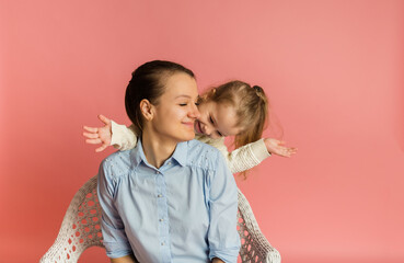 blonde daughter having fun with her mom on a pink background with a place for text
