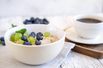 Delicious porridge with blueberry and grapes. Fresh breakfast with coffee served on grey table