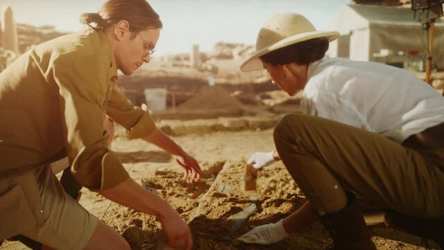Archeological Digging Site: Two Great Archeologists Work on Excavation Site, Cleaning, Lifting Newly Discovered Ancient Civilization Cultural Artifact, Historic Clay Tablet, Cuneiform, Fossil Remains