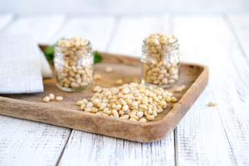 Delicious pine nuts in glass jars on wooden tray. Organic food