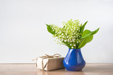 Happy spring holiday. International worker day concept. Bouquet of lilies of the valley and handmade gift box on wooden table and white background