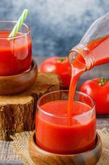 Tomato juice in glasses with straws on wooden boards