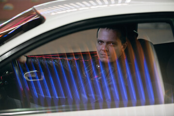 A serious driver is sitting by the car steering wheel.