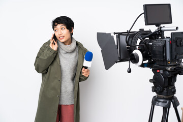 Reporter Vietnamese woman holding a microphone and reporting news keeping a conversation with the mobile phone with someone