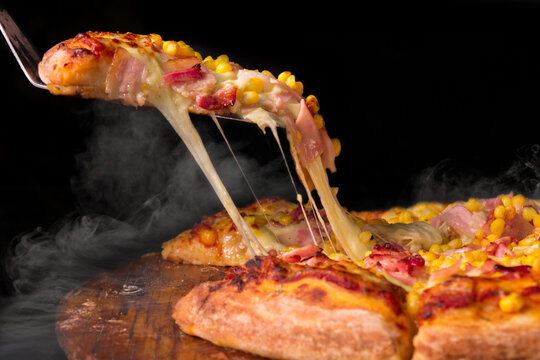 Pizza de ma&iacute;z con queso mozzarella, tocineta, pimiento, especias. Pizza italiana sobre fondo negro.