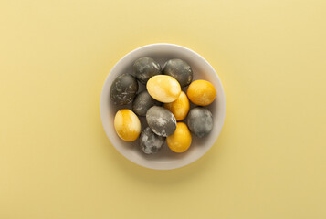 Golden and silver easter eggs in a plate isolated on yellow background