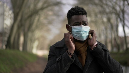 African man putting covid-19 mask, black wearing surgical face mask