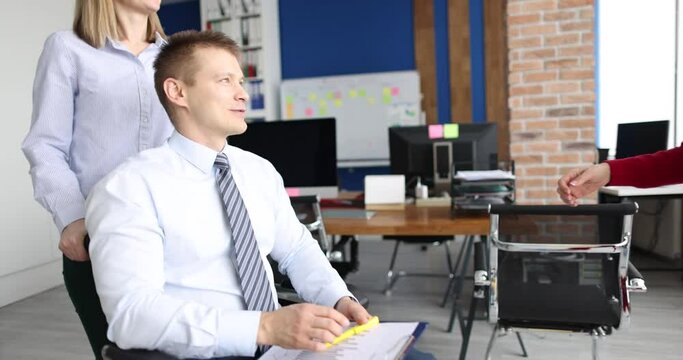 Businessman in wheelchair shaking hands with woman colleague 4k movie. Successful work of people with disabilities concept