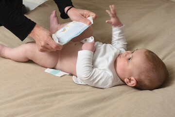 changing the diaper on the baby who is lying in bed