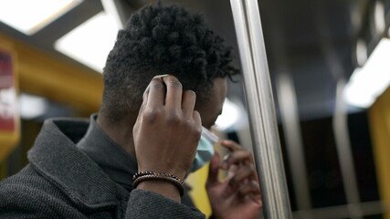 African man standing in subway metro wearing coronavirus mask underground commute

