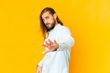 Young man with long hair look rejecting someone showing a gesture of disgust.