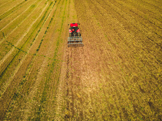 Fototapeta na wymiar Tractor mowing agricultural field. Aerial view. Cultivating field.
