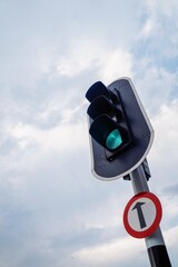 Green traffic light with cloudy sky background