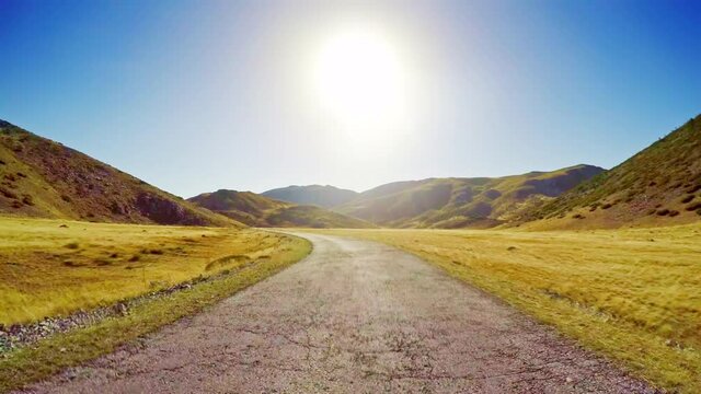 Golden grassland plateau and shining sun blue sky beautiful nature POV drive, remote countryside upland landscape, rough asphalt old road car travel point of view
