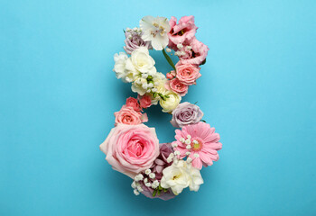 Number 8 made of beautiful flowers on light blue background, flat lay. International Women's day