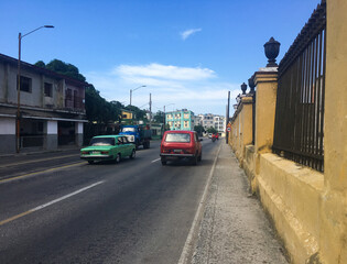 Havana street with sidewalk on the right side and road on the left side, during a sunny day with blue sky.