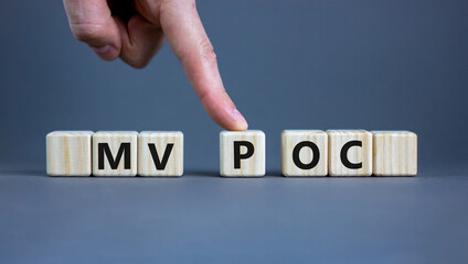 MVP vs POC symbol. Businessman pushes the cube with words MVP, minimum viable product and POC, proof of concept. Beautiful grey background. Business and MVP vs POC concept, copy space.