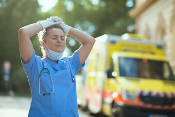 relaxed paramedic woman breathing outdoors near ambulance