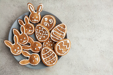 Easter cookies in the shape of bunnies and eggs on a gray plate and a grey stone background,Top view