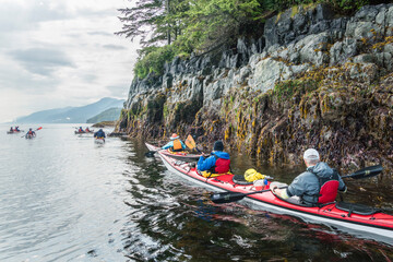 Canada, British Columbia. Sea kayakers paddle at low tide along the Vancouver Island shore on Johnstone Strait.
