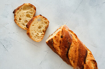 Sliced freshly baked French baguette on light background.