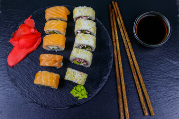 Set of sushi rolls on a black stone slate. Top view
