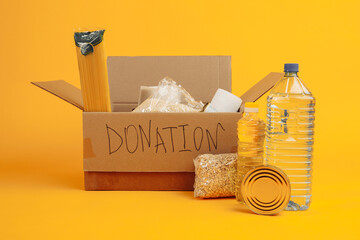 Donation box with food isolated on yellow background.