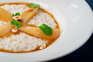 Oatmeal milk porridge with pear and caramel syrup on a blue wooden table. Healthy eating, healthy food for Breakfast, close up