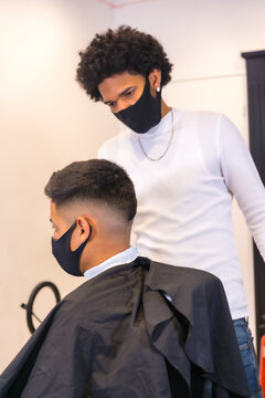 Hairdresser with mask and gloves cutting hair. Security measures of Hairdressers in the Covid-19 pandemic, vertical photo