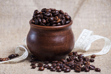 Coffee beans scattered on the table from a clay pot