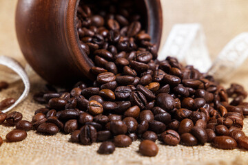 Coffee beans in a clay pot on a textured background.