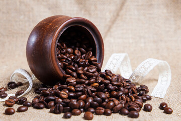 Coffee beans in a clay pot on a textured background.