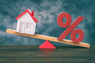 Wooden seesaw with house and percent on desk. Mortgage rate balance concept. 3d illustration