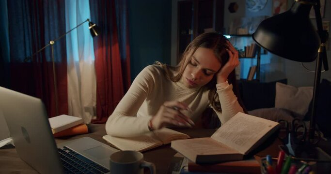Tired young woman student trying to study in the night at home, busy overworked, remote learning during coronavirus covid 19 lockdown, preparation for exam, stressed depressed female.