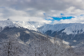 Fototapeta na wymiar Beautiful winter landscape with snow covered trees and mountains peaks. Caucasus mountain view from Roza Khutor