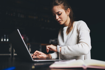 Focused woman looking at watch working at night