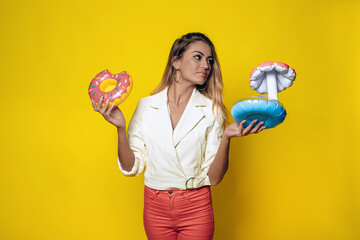 Charming slender girl with a great figure and blond hair holding small inflatable beach toys in her...
