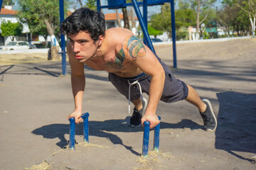 Fototapeta na wymiar shirtless tattooed man doing push ups exercise in park, earphones 