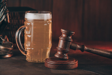 Glass of beer and judge gavel as a symbol of law on a wooden table.