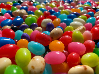 Fototapeta na wymiar closeup view looking at gourmet flavored jelly beans in various colors with shining light above
