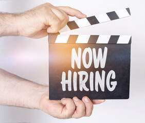Obraz premium On a white background, a man holds a clapperboard in his hands on which it is written - NOW HIRING