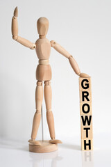 The wooden man raised his hand, and under his left hand he has cubes with the inscription - GROWTH