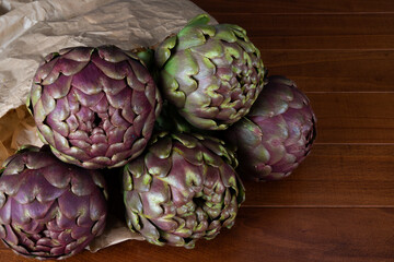 Roman artichokes on the wooden table. Fresh and raw artichokes.