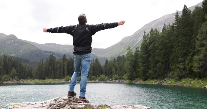 Male standing on rock with arms wide enjoying freedom, solo traveler
