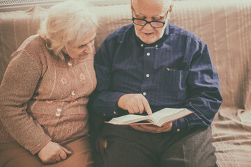 Elderly couple reading bible and pray together at home.