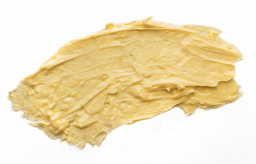 Yellow cosmetic cream body butter smeared on a white background.