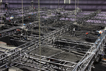Black steel trusses are lifted by chain hoists. Installation of professional rigging equipment for...